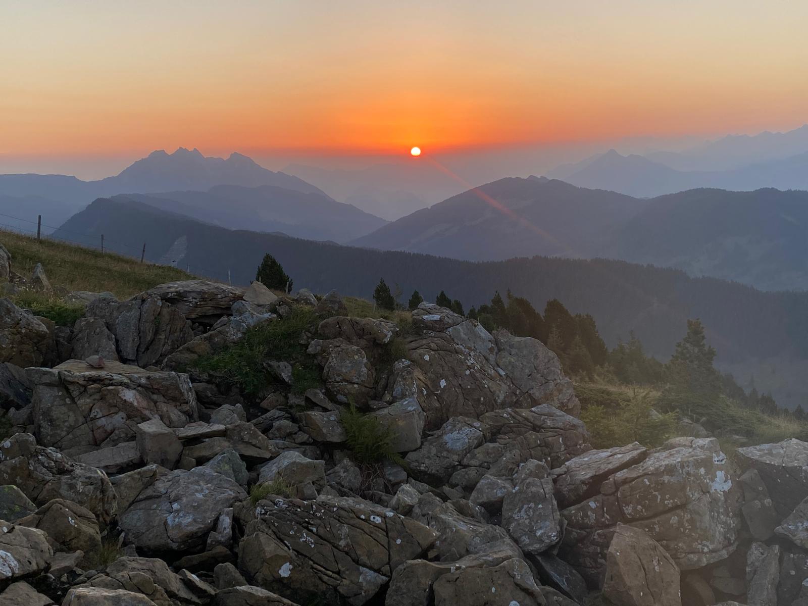 Fast vollständig aufgegangene Sonne in hellgelb-weißem Strahlen im Morgenrot, gesehen vom Rickhubel